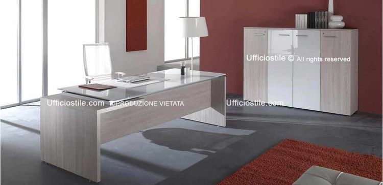 Composizione ufficio Rovere Portofino Comp. 24 con scrivania direzionale da 180 x 90 cm con piano in vetro temperato retroverniciato bianco e fianco ribassato, abbinata a libreria media da 180 x 45 x 130 cm con due ante cieche laterali, coppia di ante centrali in vetro temperato retroverniciato bianco con telaio in alluminio, top e fianchi di finitura.