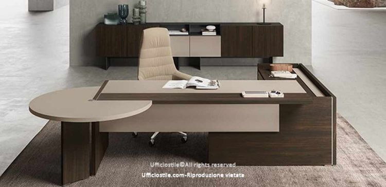 Composizione direzionale con scrivania dotata di piano scorrevole lato operatore, modesty panel in melaminico cappuccino o nocciola, mobile di servizio portante con anta scorrevole soft-closing e serratura, penisola con gamba per riunioni o collaborazione e madia a sei moduli su basi con carter di copertura.