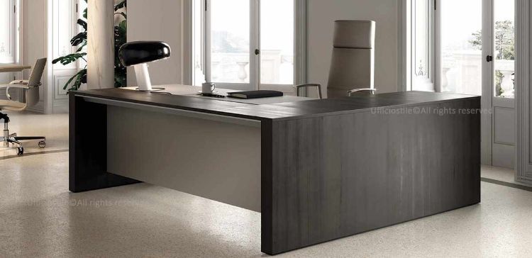 Scrivania direzionale angolare Ono da 200 x 200 cm con piano in essenza verniciata spessore 20 mm, bordo perimetrale in tranciato di legno spessore 2 mm, formelle in MDF rivestite in vera pelle, formella centrale scorrevole su guide metalliche con escursione di 10 cm e dispositivo di sicurezza integrato per accesso al cablaggio nella vasca metallica.