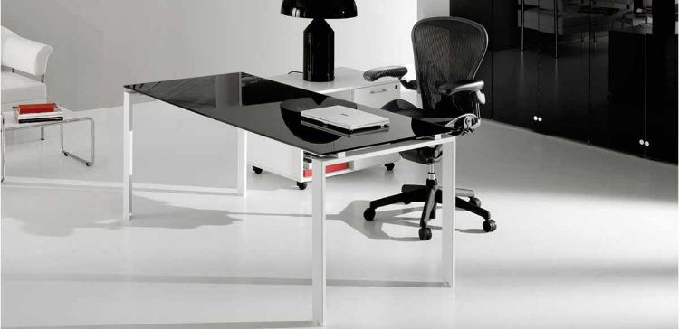 Scrivania Linea Ufficiostile 02 con piano in vetro temperato retroverniciato bianco spessore 10 mm, struttura metallica a ponte stile industriale con gambe a U rovesciata e mobile di servizio su ruote con tre cassetti, vano a giorno con ripiano e dimensioni 90 x 60 x 62 cm.