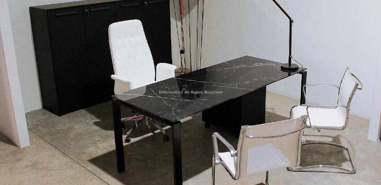 Scrivania direzionale da 180 x 80 cm con piano in vetro temperato spessore 10 mm retroverniciato effetto marmo, struttura metallica verniciata a polveri epossidiche con gambe a ponte, libreria a 4 ante cieche con serratura composta da due moduli e cassettiera su ruote a tre cassetti con rallentatori in finitura nera.