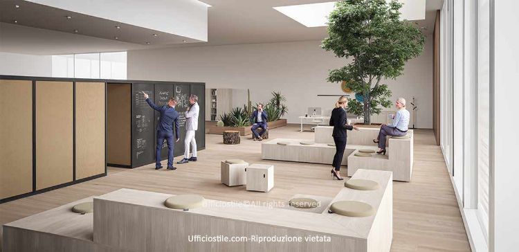 Spazio collaborativo per uffici moderni con arena modulare in legno chiaro, sedute su più livelli con cuscini removibili, parete attrezzata con superficie scrivibile tipo lavagna, albero naturale indoor integrato in un grande volume con funzione di seduta, sgabelli in legno, piani d’appoggio, postazioni operative minimal e cubi mobili da 45 x 45 cm su ruote utilizzabili come pouf o tavolini portaoggetti.