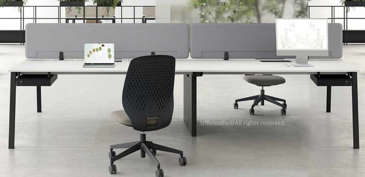 Bench operativo a quattro posti composto da quattro scrivanie da 180 cm, con strutture metalliche a cavalletto, gamba intermedia a ponte completa di carter, due frontal panels rivestiti in tessuto e due cassetti sospesi sottopiano, realizzato in conglomerato ligneo rivestito in melaminico e prodotto Made in Italy.