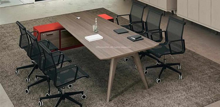 Tavolo riunioni design asimmetrico con piano in MDF impiallacciato, tappo passacavi cromato integrato, gambe in legno massello stondate e verniciate, mobile di servizio portante sottopiano con due ante, modulo tecnico e cestello portacavi per sale riunioni e uffici direzionali.