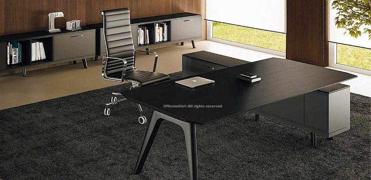 Scrivania direzionale nera in MDF impiallacciato spessore 30 mm con due gambe in legno massello stondate, levigate e verniciate, abbinata a mobile di servizio portante con anta, due cassetti, modulo tecnico e cestelli passacavi per uffici direzionali moderni.
