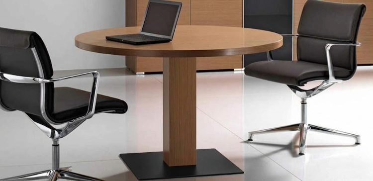 Tavolo riunioni tondo in legno con piano spessore 39 mm, base a pianta a sezione quadrata e piastra cromata, disponibile nelle finiture Wengè o Noce americano, ideale per sale riunioni, uffici direzionali e ambienti conference professionali.